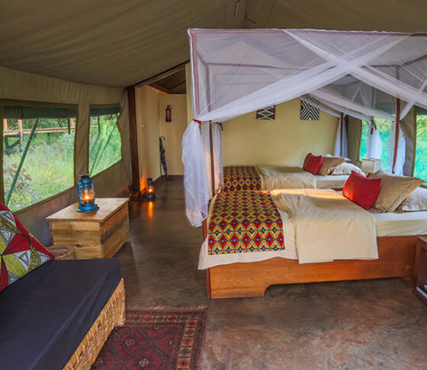 Inside a tent lodge in Ruzizi with two beds and a couch.