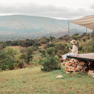 Woman sitting on the deck looking out at the valley and mountains in Akagera National Park